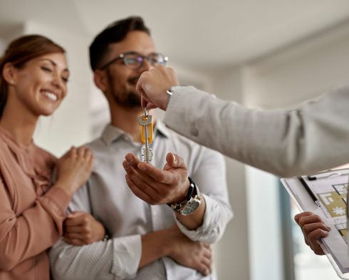 Close-up of a real estate agent giving to a couple keys of their new home.