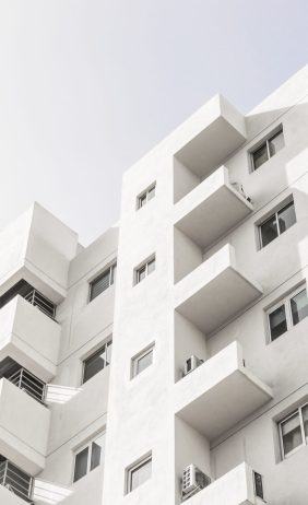 A low angle shot of a facade of a white modern building under a blue clear sky