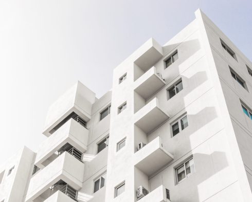 A low angle shot of a facade of a white modern building under a blue clear sky
